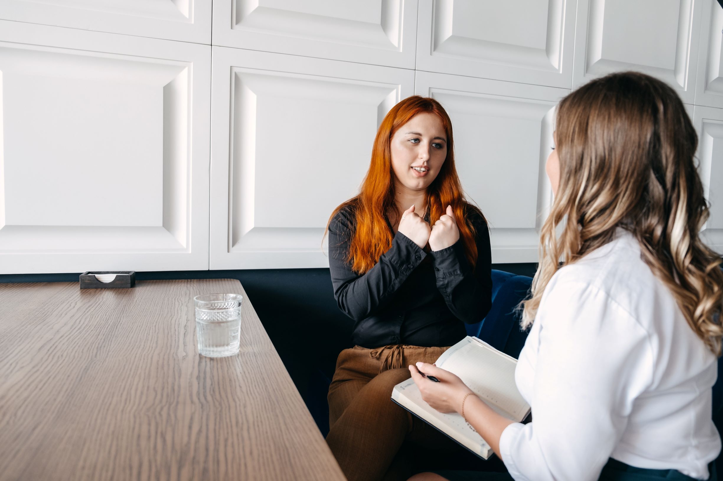 Two ladies chatting while sat at a desk