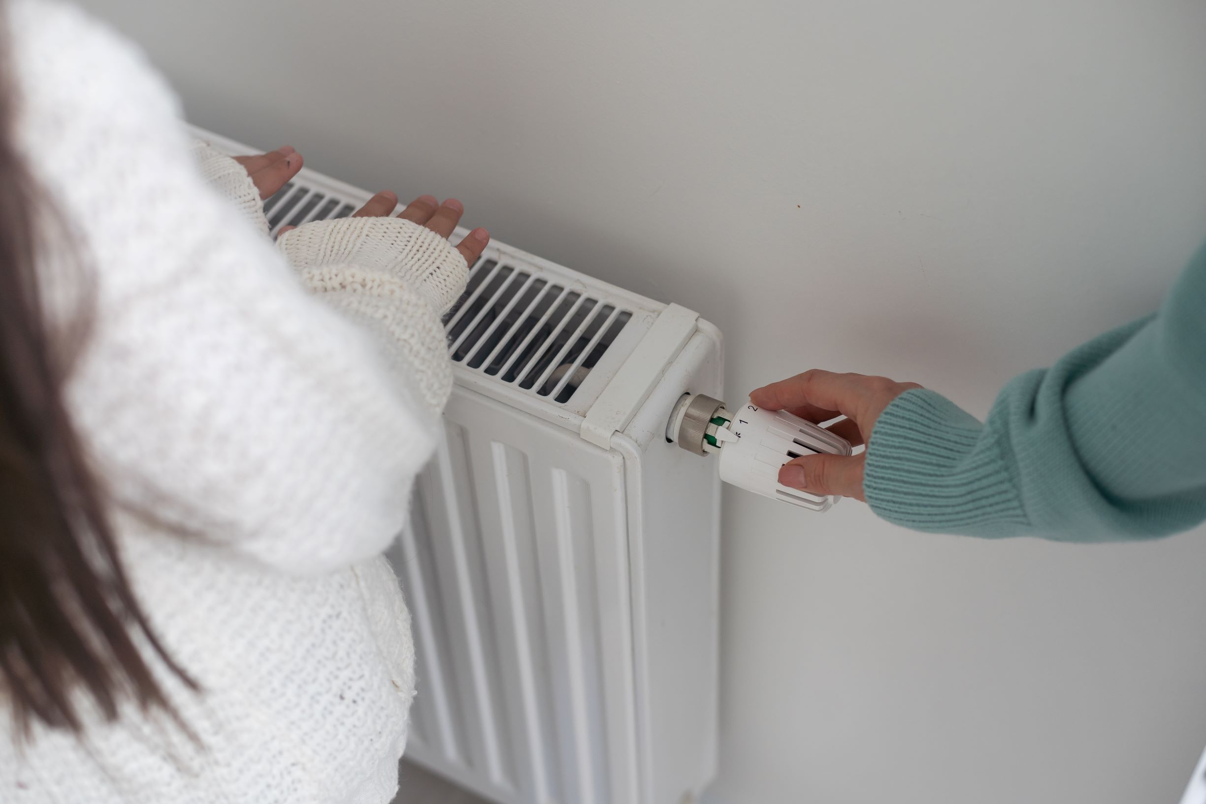 Woman turning up thermostat on radiator