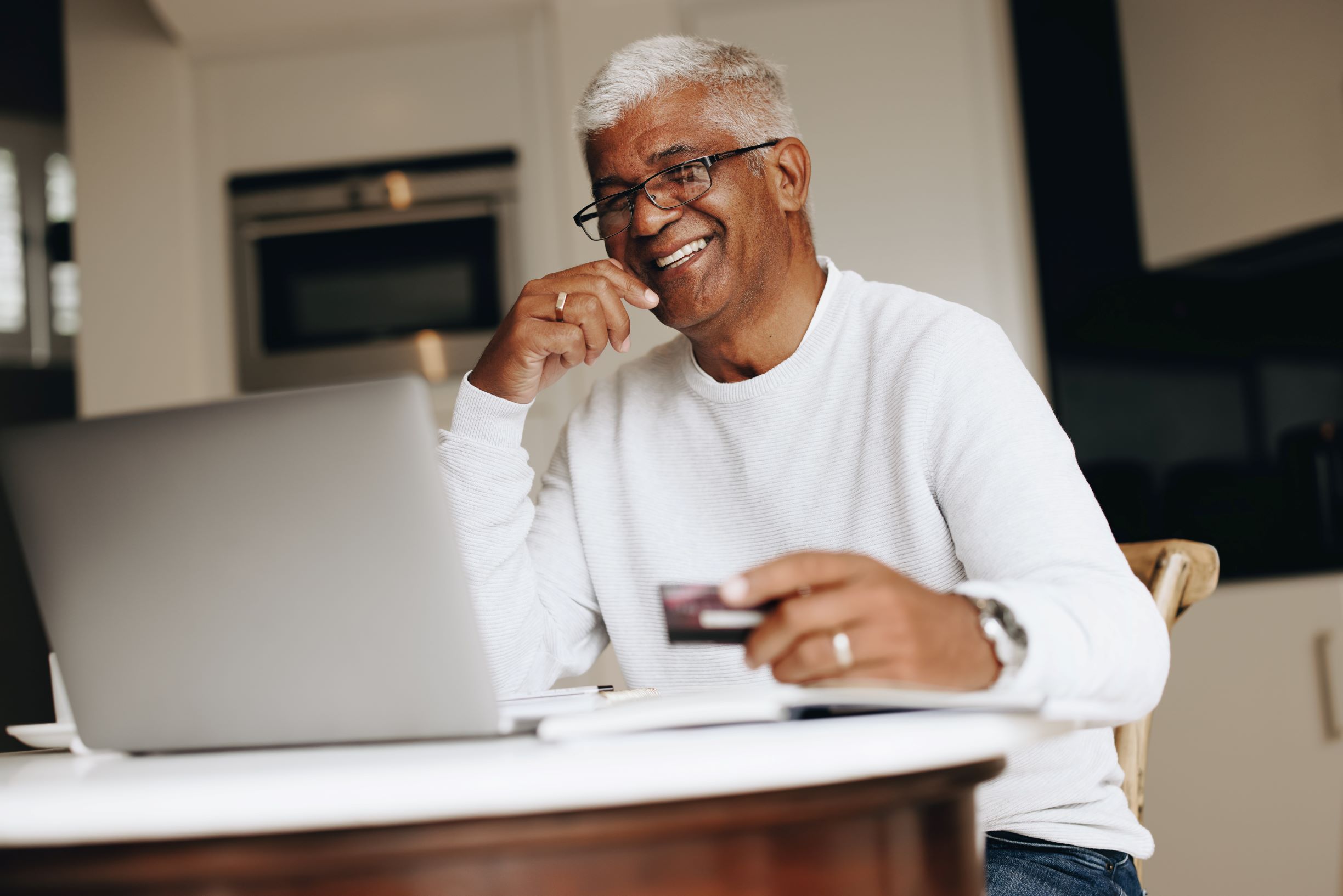 Man using his laptop in the kitchen for online shopping