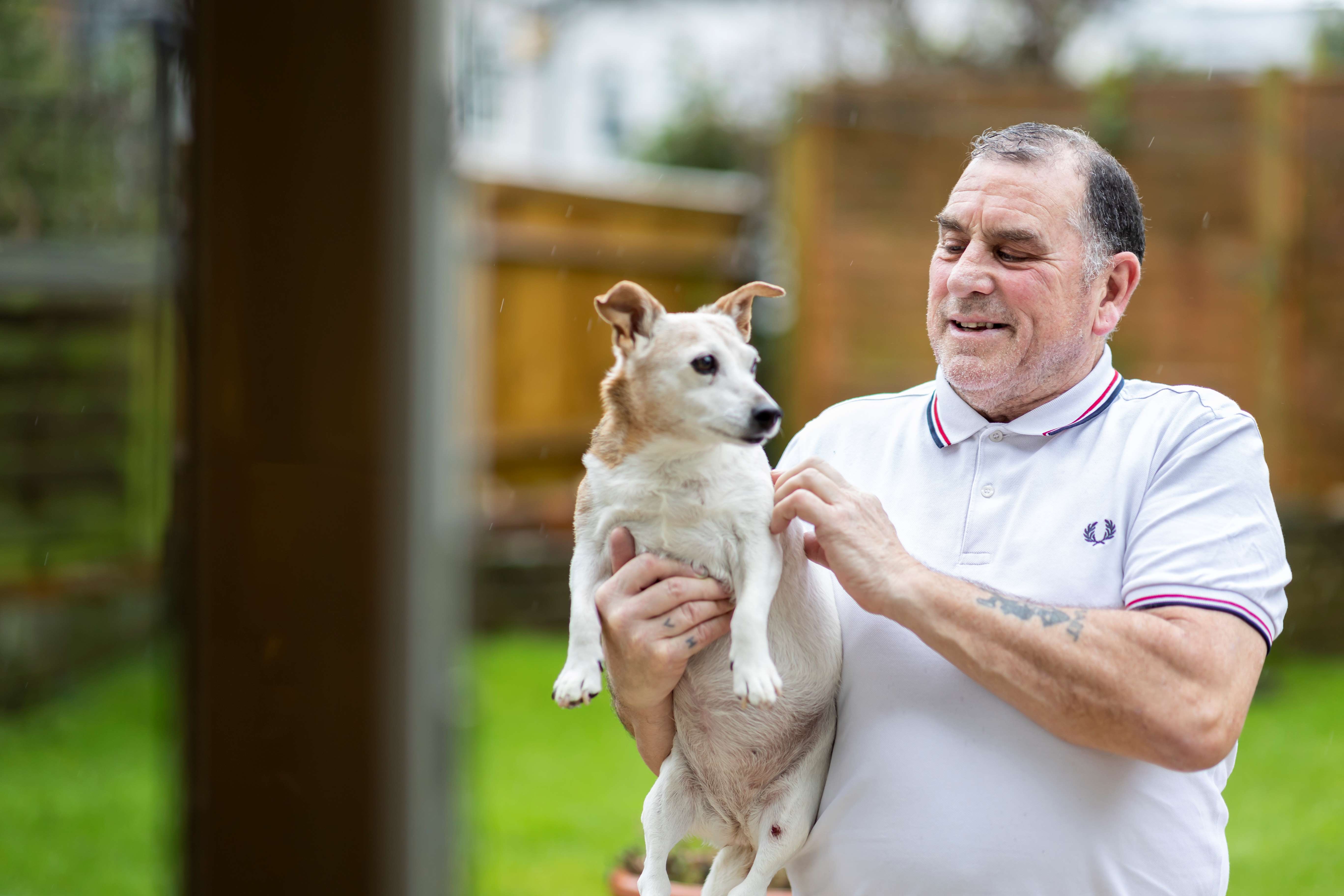 Man holding his dog in the garden