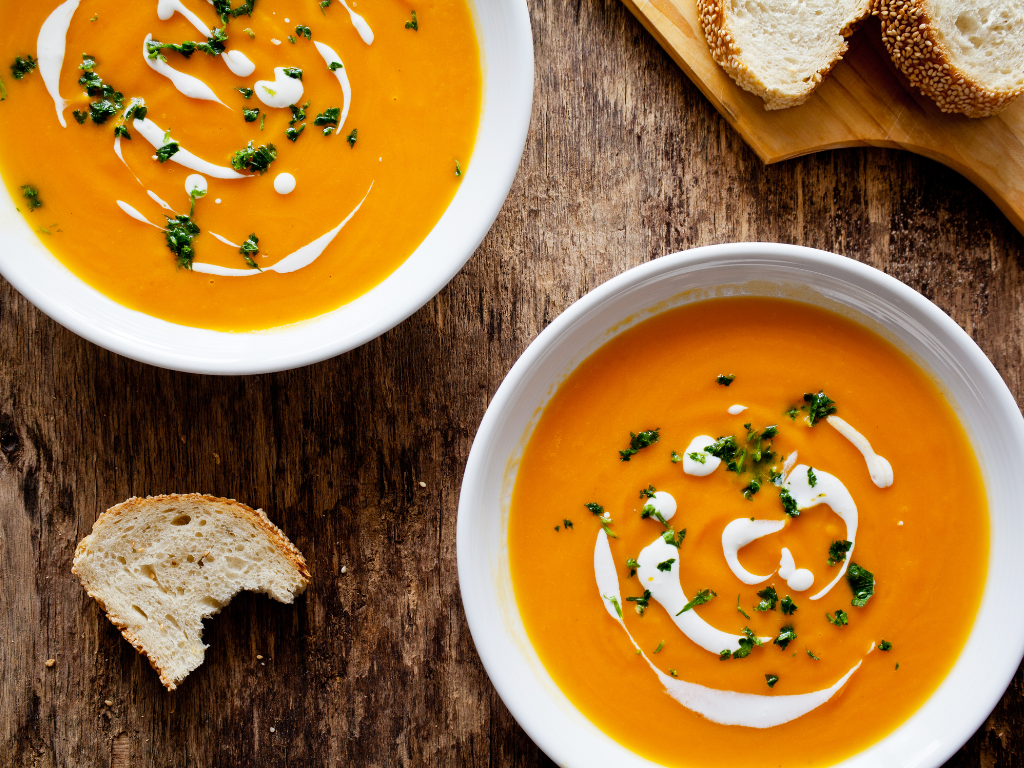 a photo of soup in a bowl with some bread