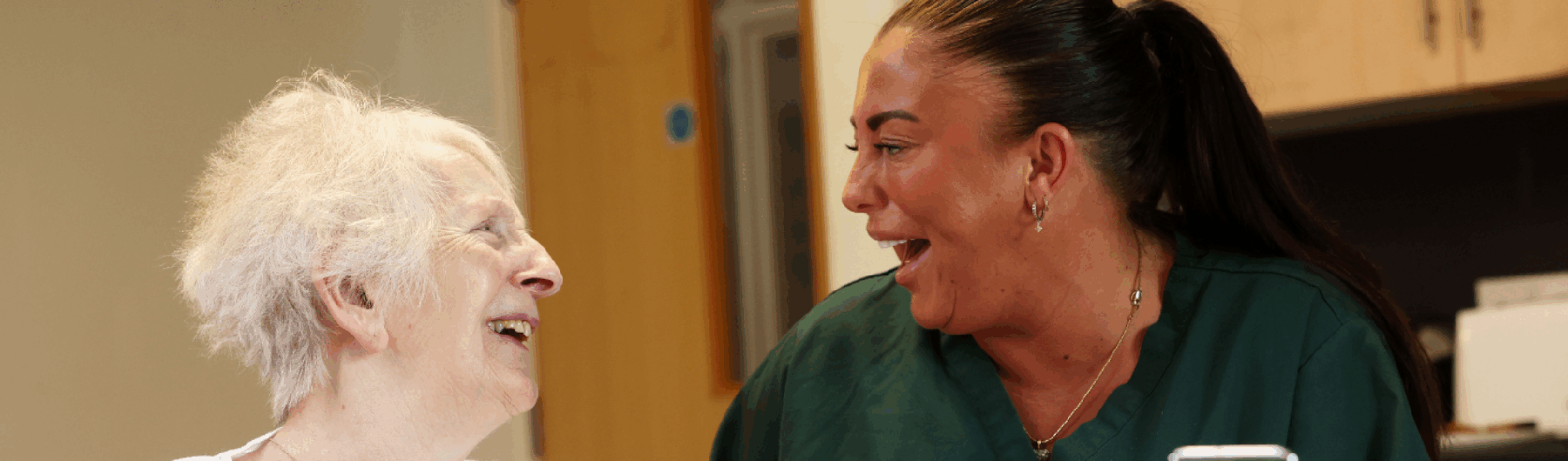 Female care home resident laughing with carer